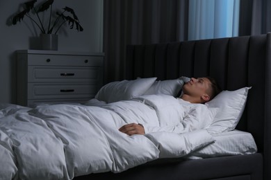 Photo of Young man sleeping in soft bed at night