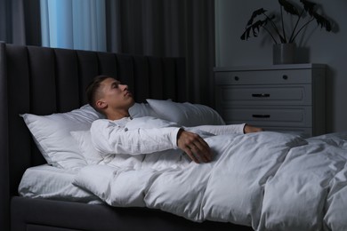 Photo of Young man suffering from sleepwalking on bed at home