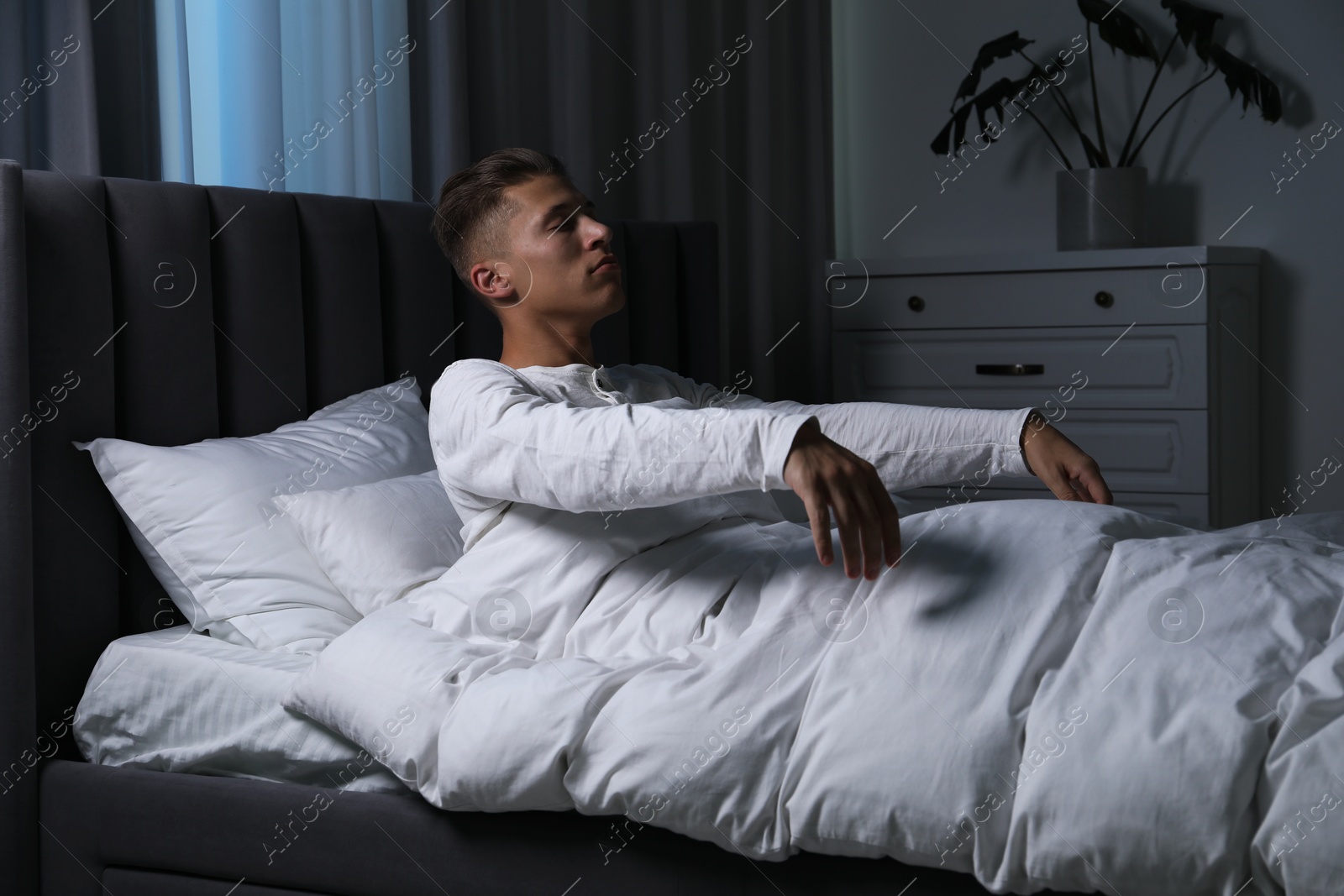 Photo of Young man suffering from sleepwalking on bed at home