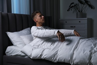 Photo of Young man suffering from sleepwalking on bed at home