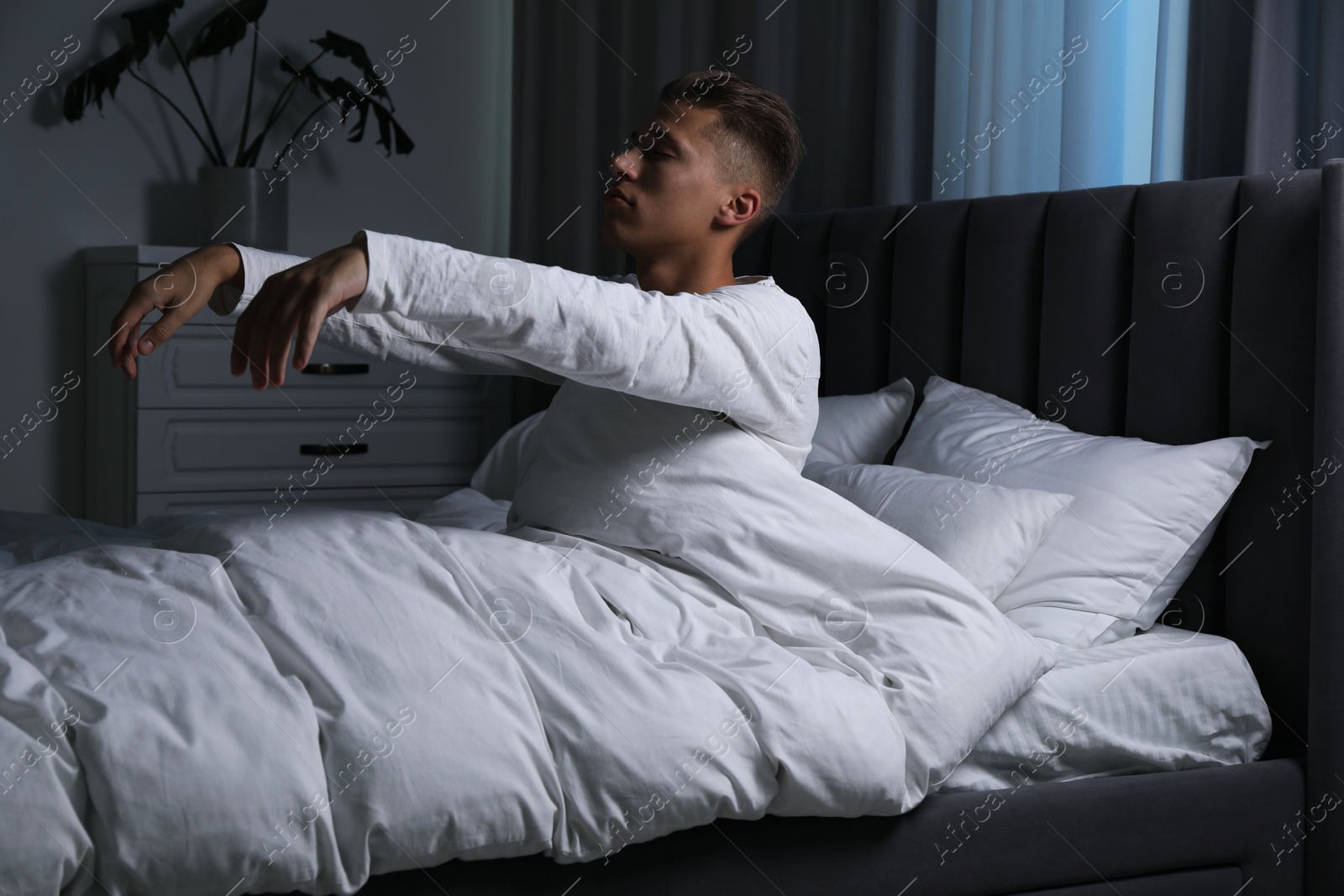 Photo of Young man suffering from sleepwalking on bed at home