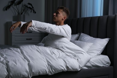 Photo of Young man suffering from sleepwalking on bed at home