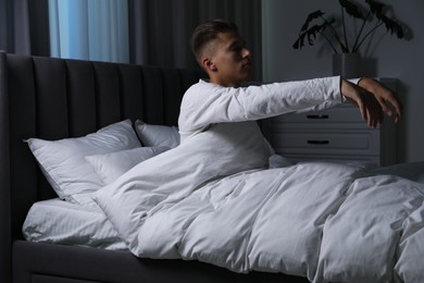 Photo of Young man suffering from sleepwalking on bed at home