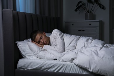 Photo of Young man sleeping in soft bed at night