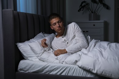 Photo of Young man suffering from sleepwalking on bed at home