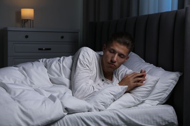 Photo of Young man suffering from sleepwalking on bed at home