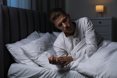 Photo of Young man suffering from sleepwalking on bed at home