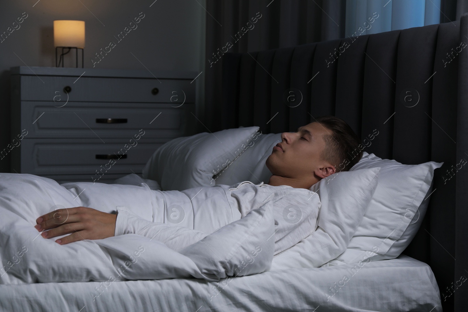 Photo of Young man sleeping in soft bed at night