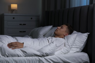 Photo of Young man sleeping in soft bed at night