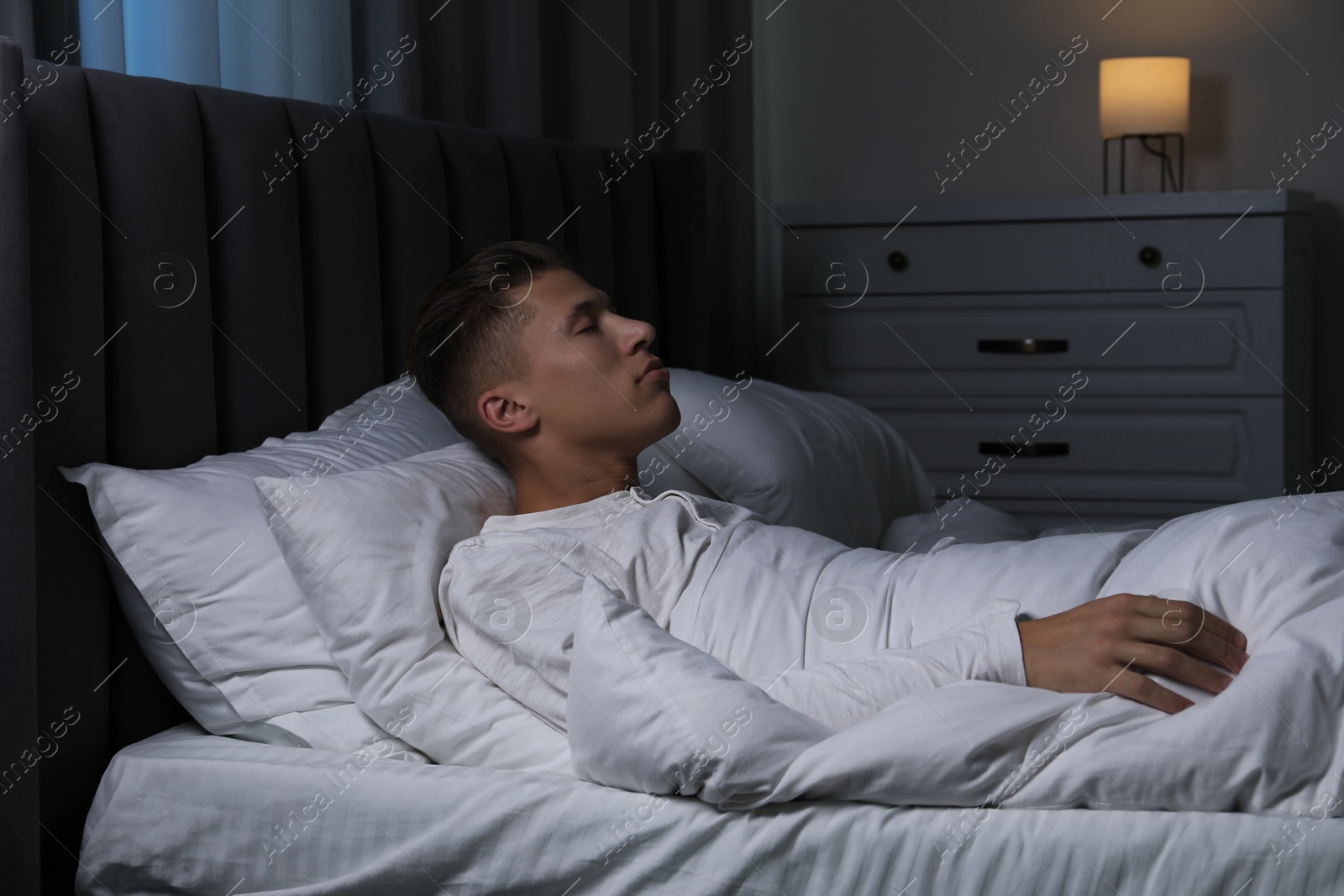 Photo of Young man suffering from sleepwalking on bed at home