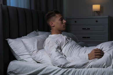 Photo of Young man suffering from sleepwalking on bed at home