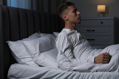 Photo of Young man suffering from sleepwalking on bed at home