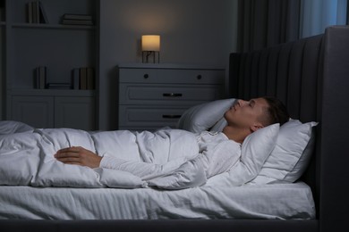 Photo of Young man sleeping in soft bed at night