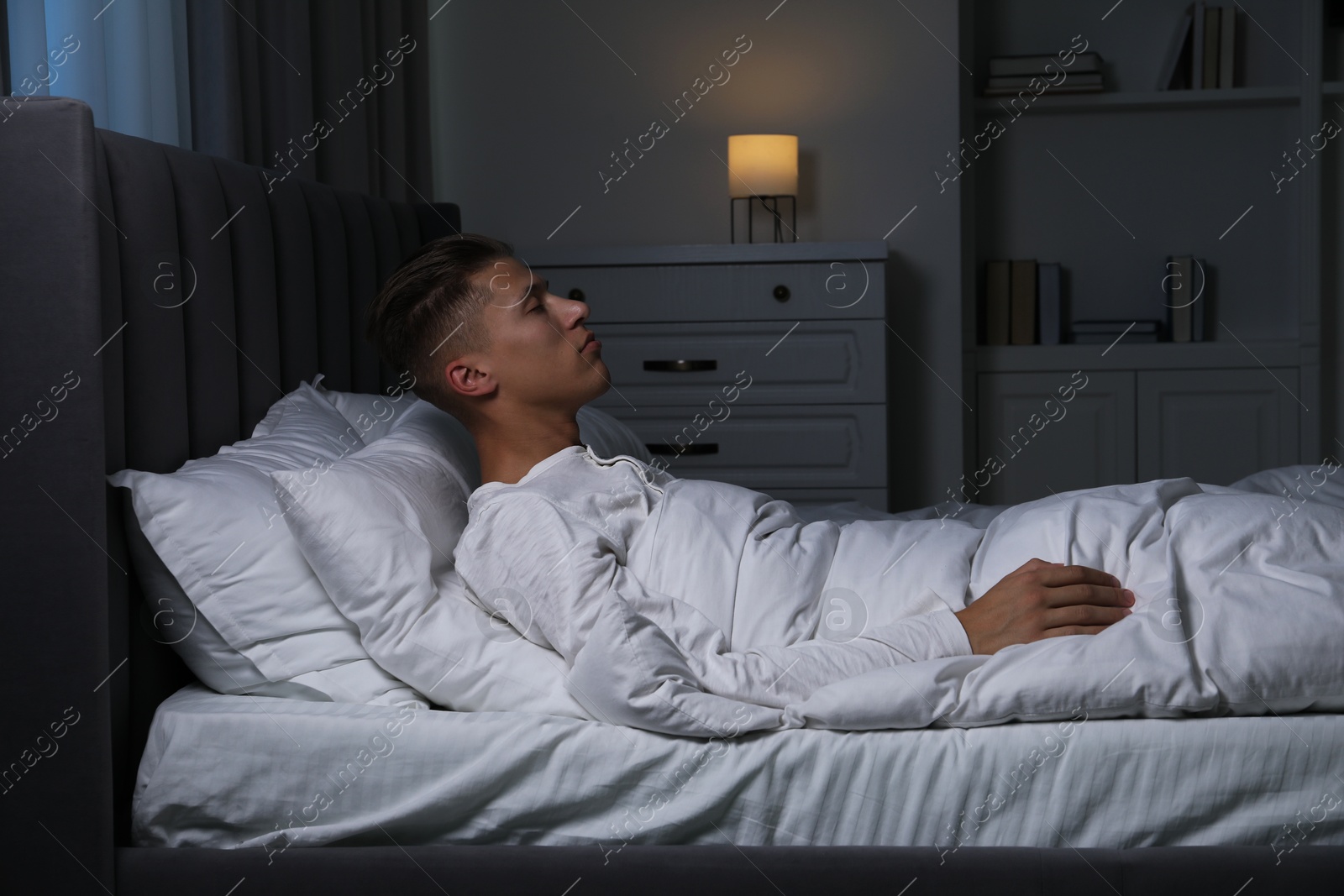 Photo of Young man suffering from sleepwalking on bed at home