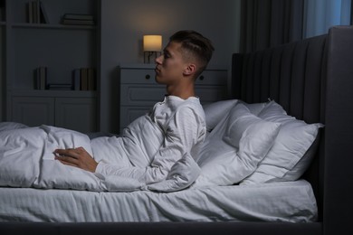 Photo of Young man suffering from sleepwalking on bed at home