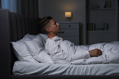 Photo of Young man suffering from sleepwalking on bed at home