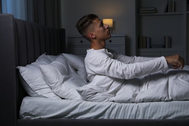 Photo of Young man suffering from sleepwalking on bed at home