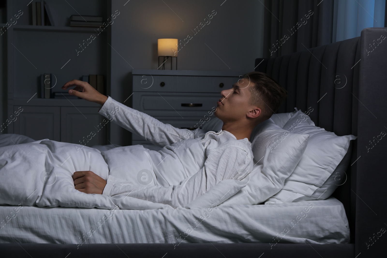 Photo of Young man suffering from sleepwalking on bed at home