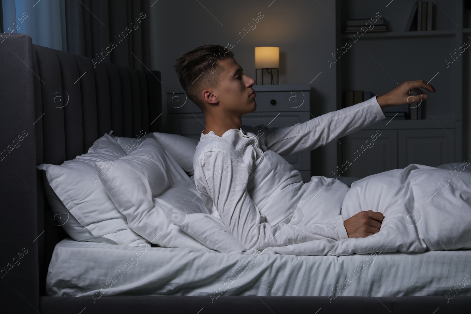 Photo of Young man suffering from sleepwalking on bed at home