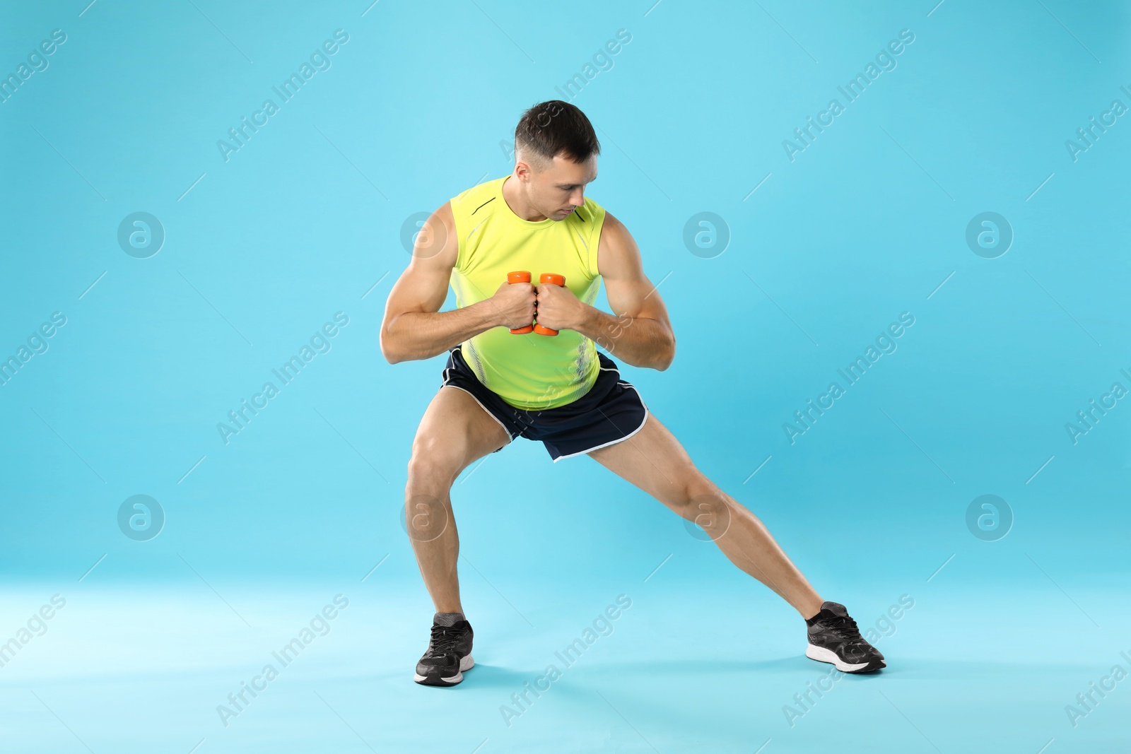 Photo of Man exercising with dumbbells on light blue background