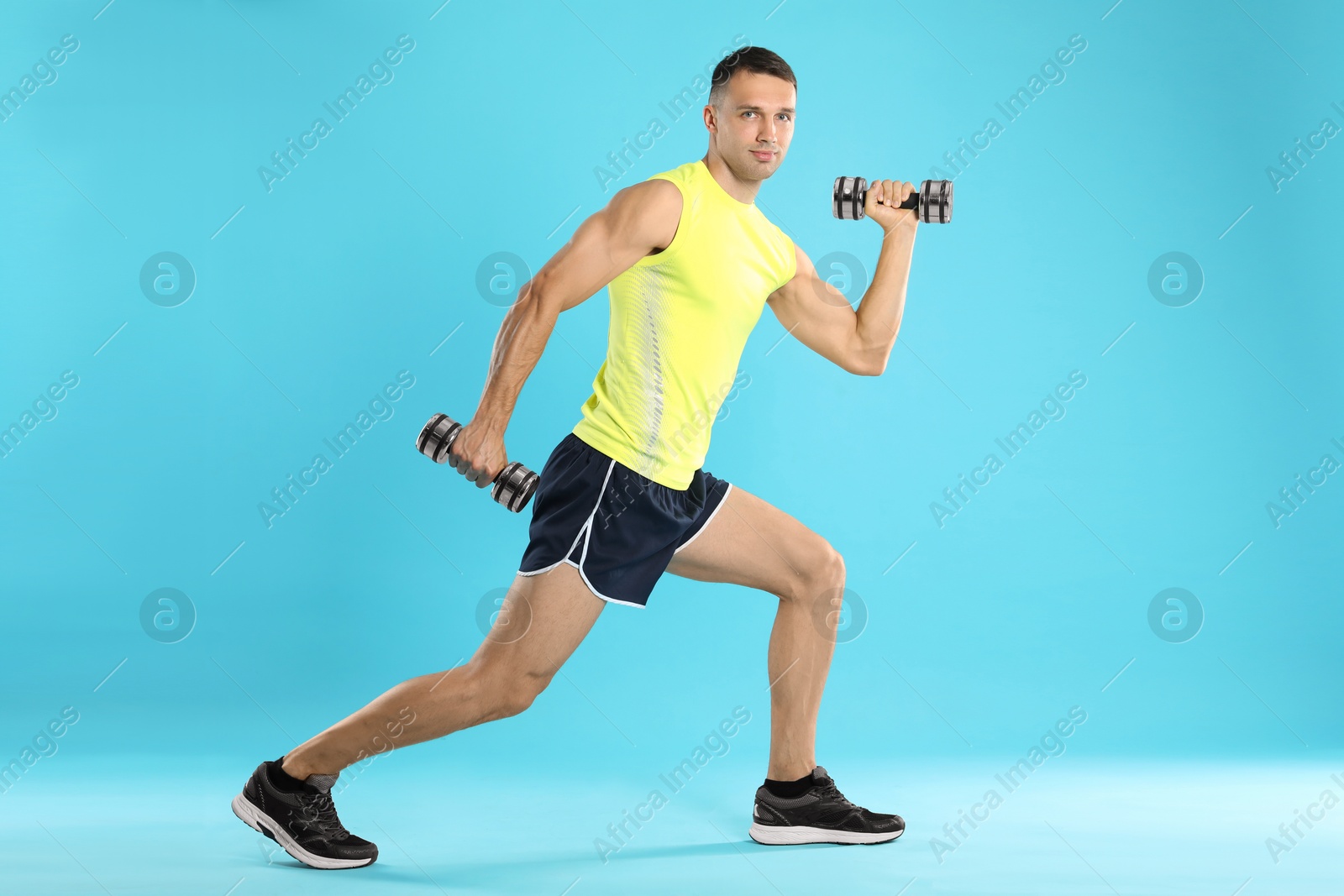 Photo of Man exercising with dumbbells on light blue background