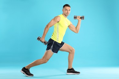 Photo of Man exercising with dumbbells on light blue background