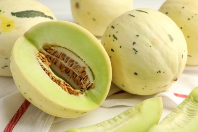 Photo of Fresh whole and cut honeydew melons on white wooden table, closeup