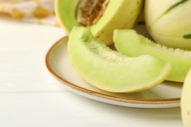 Photo of Fresh whole and cut honeydew melons on white wooden table, closeup