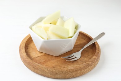 Photo of Cut tasty melon in bowl on white table