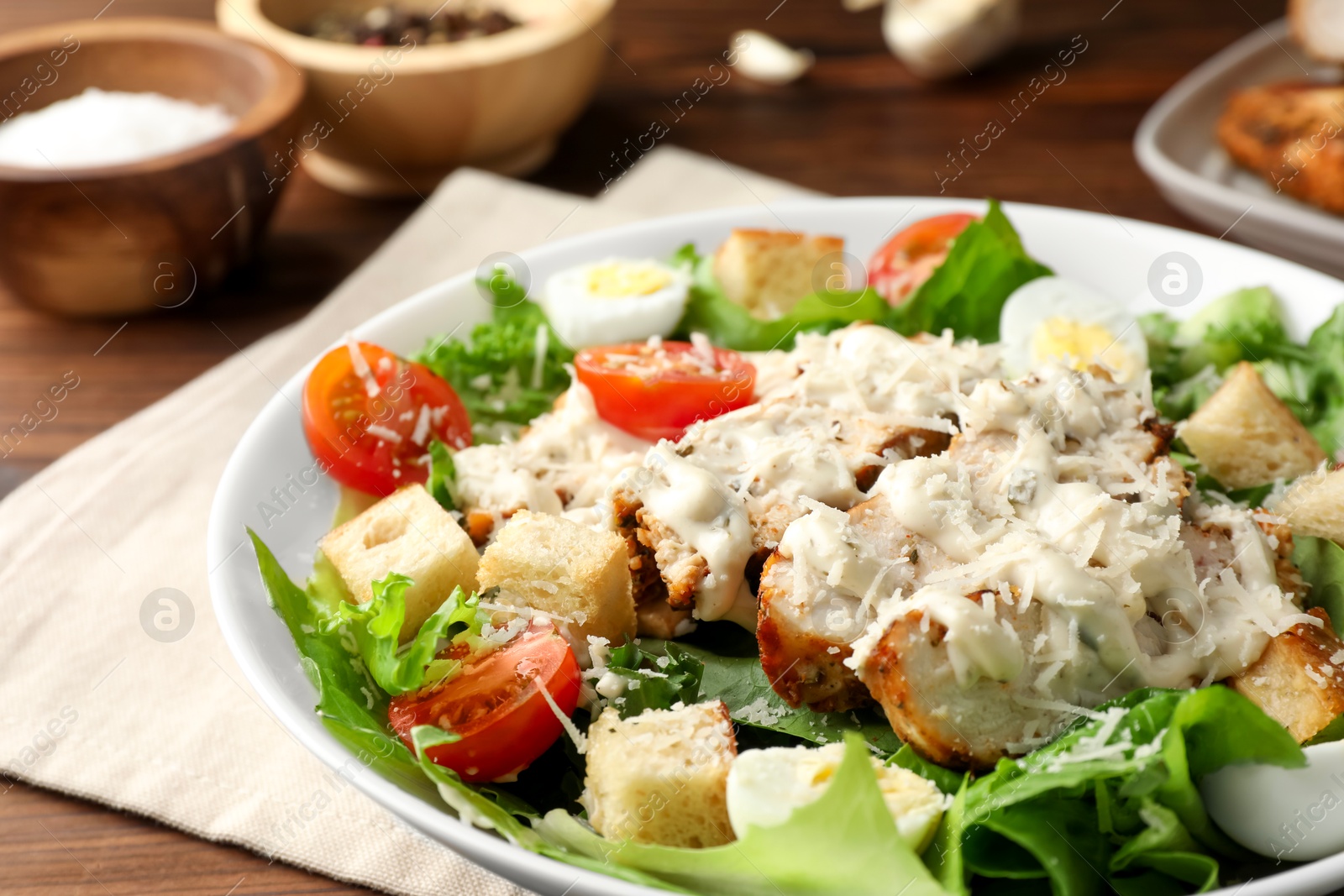 Photo of Tasty Caesar salad with chicken in bowl on table, closeup