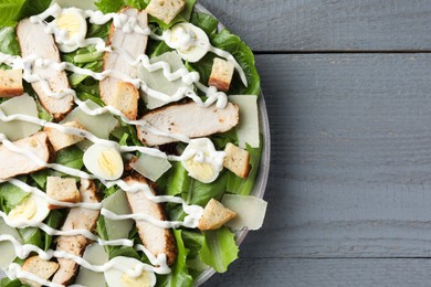 Photo of Delicious Caesar salad with chicken on grey wooden table, top view. Space for text