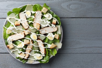 Photo of Delicious Caesar salad with chicken on grey wooden table, top view. Space for text