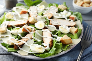 Photo of Delicious Caesar salad with chicken on grey wooden table, closeup