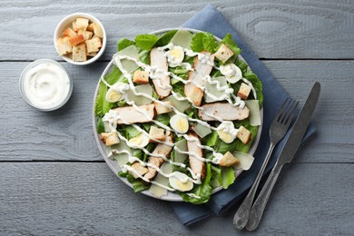 Photo of Delicious Caesar salad with chicken served on grey wooden table, flat lay