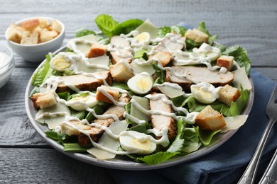 Delicious Caesar salad with chicken on grey wooden table, closeup