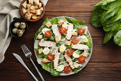 Photo of Delicious Caesar salad with chicken served on wooden table, flat lay