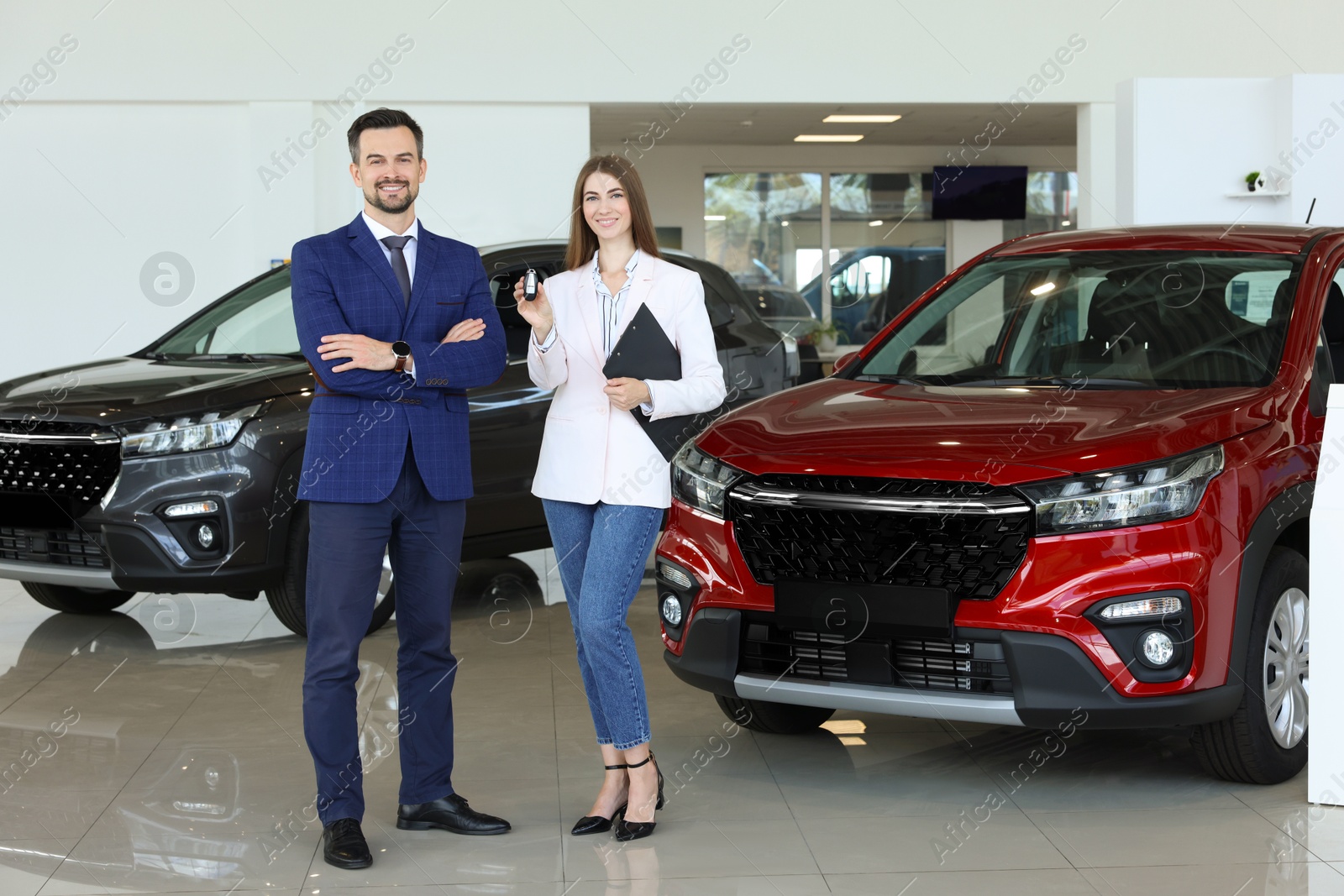 Photo of Salesman and client near new red car in salon