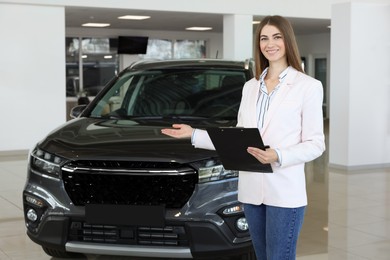 Happy saleswoman near new black car in salon