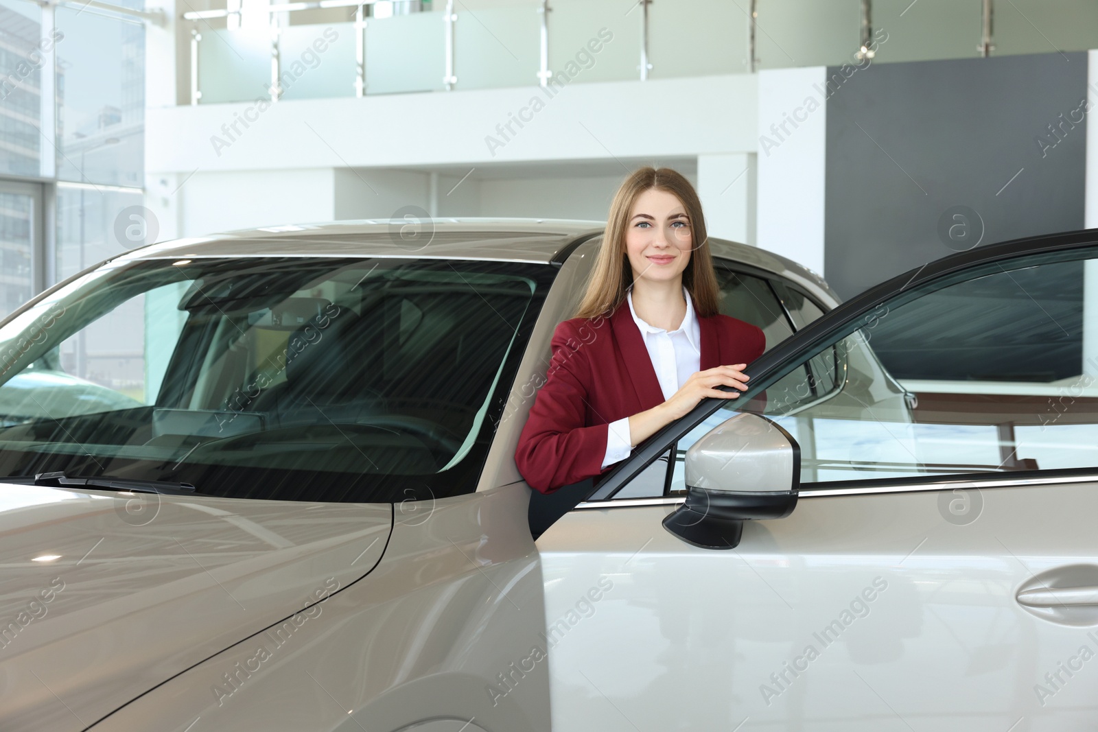 Photo of Happy saleswoman near new silver car in salon