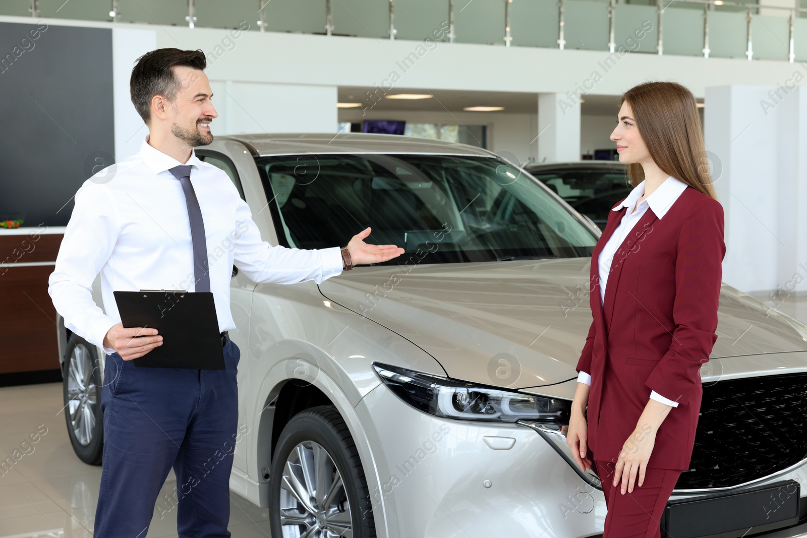 Photo of Salesman and client near new car in salon