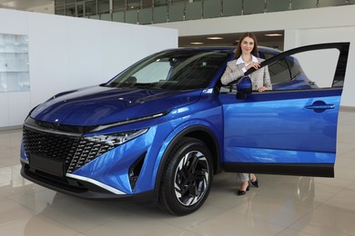 Young woman near new blue car in salon