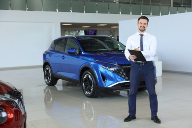 Photo of Happy salesman near new blue car in salon