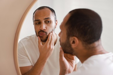 Photo of Worried man looking at mirror in bathroom