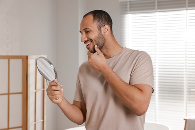 Photo of Smiling man looking at mirror in room