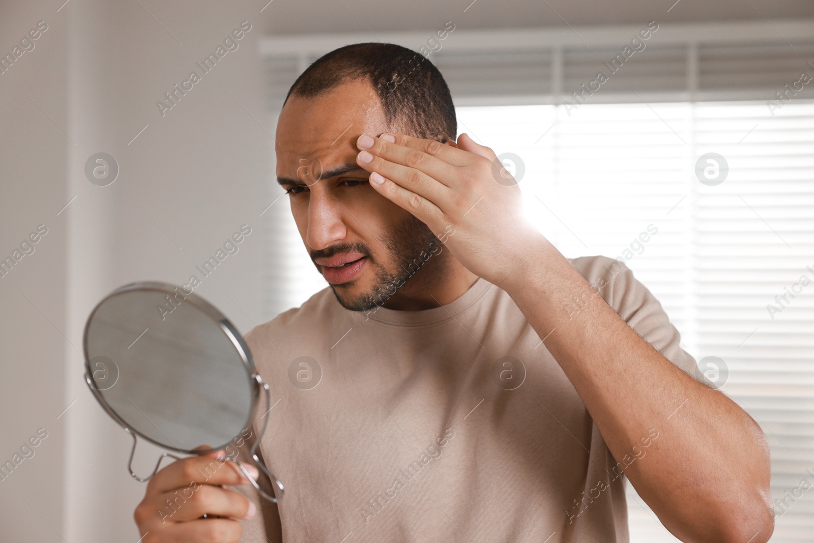 Photo of Worried man looking at mirror in room