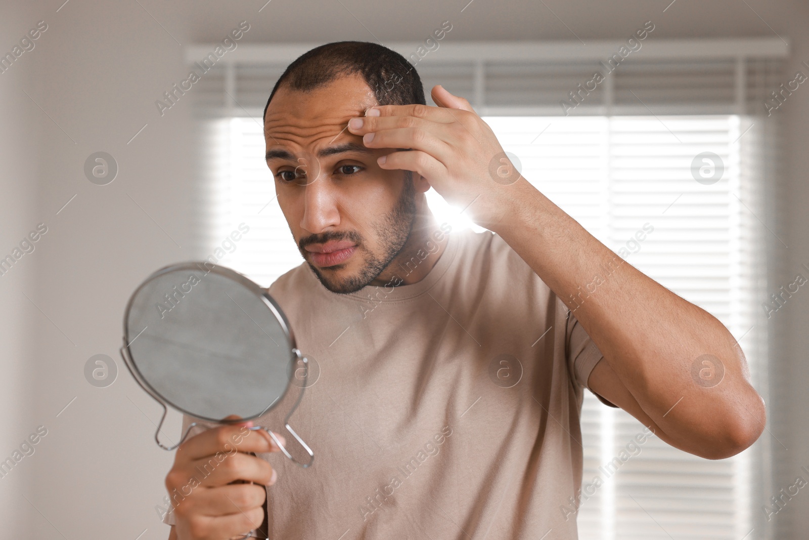 Photo of Worried man looking at mirror in room