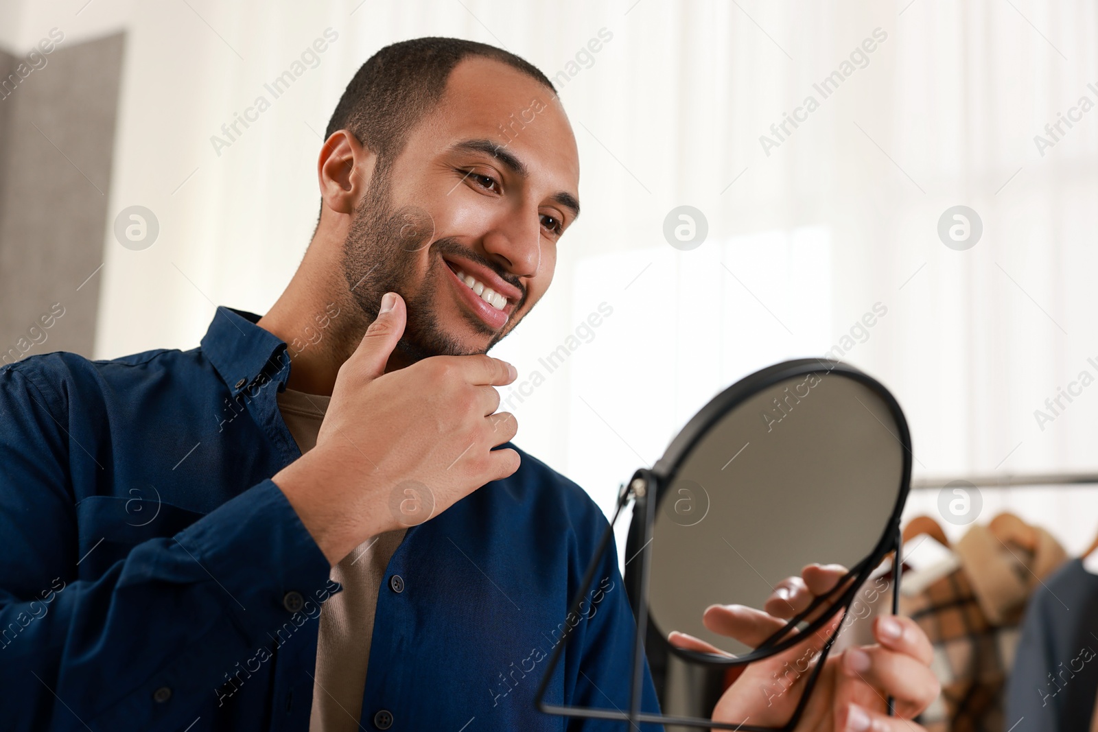 Photo of Smiling man looking at mirror at home