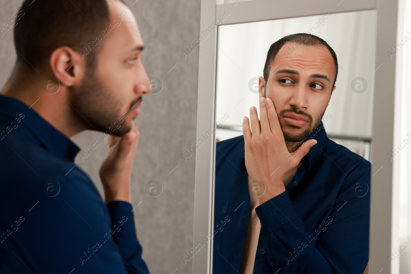 Photo of Handsome man looking at mirror at home