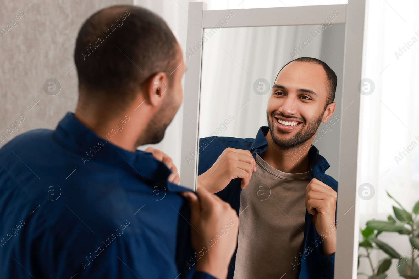 Photo of Smiling man looking at mirror at home