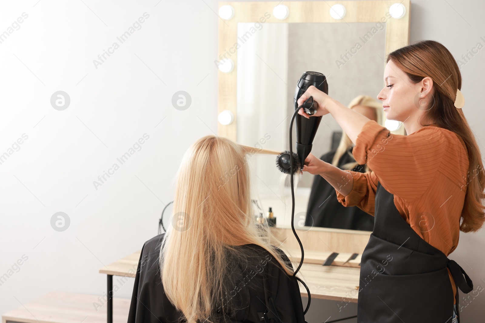 Photo of Hairdresser blow drying client's hair in salon